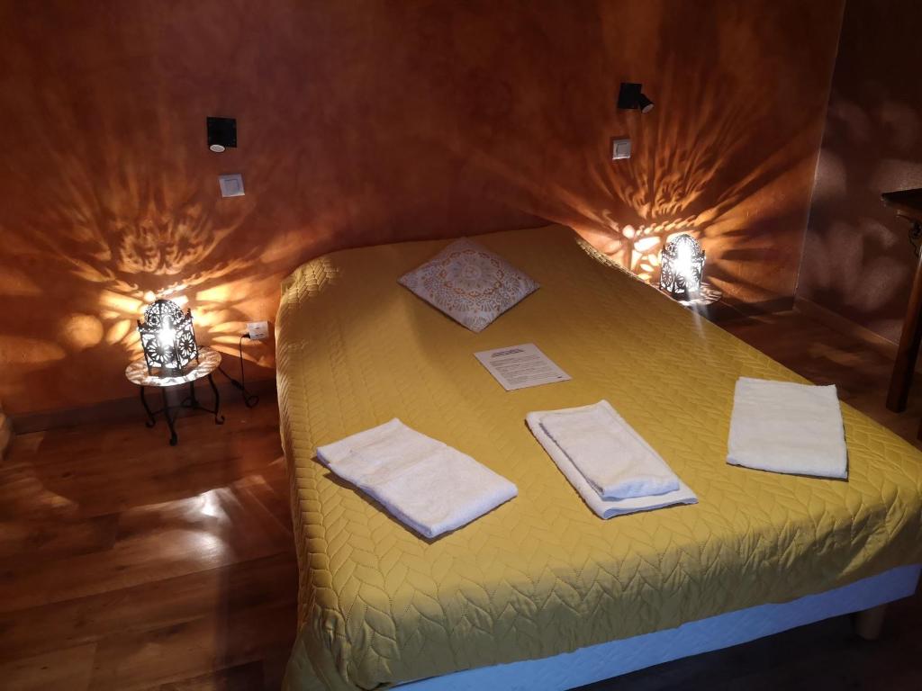 a bedroom with a yellow bed with towels on it at Domaine de la Borde in Damparis