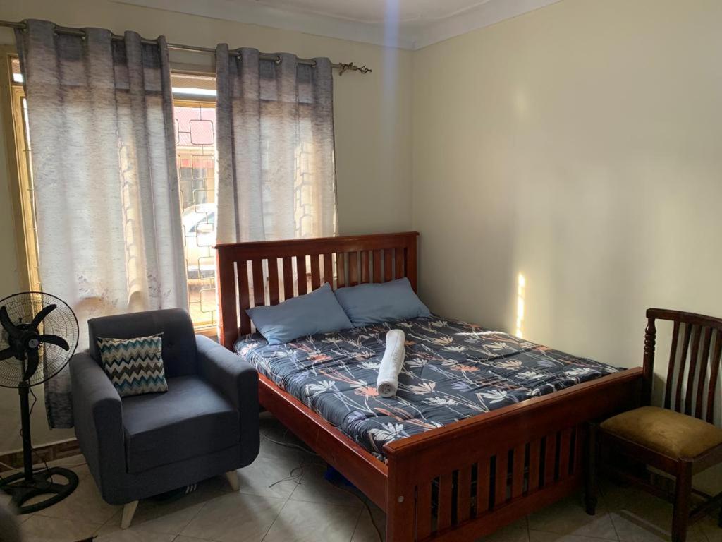 a bedroom with a bed and a chair and a window at Bukoto pal in Kampala