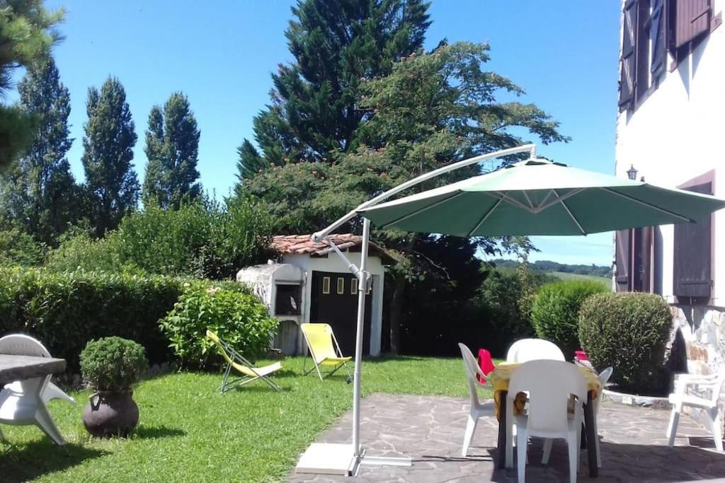 un patio con sombrilla y sillas en el césped en Logement calme et authentique à Espelette, en Espelette