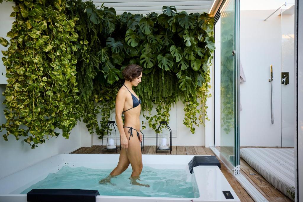 a woman in a bathing suit standing in a bath tub at Musae Relais & SPA in Polignano a Mare
