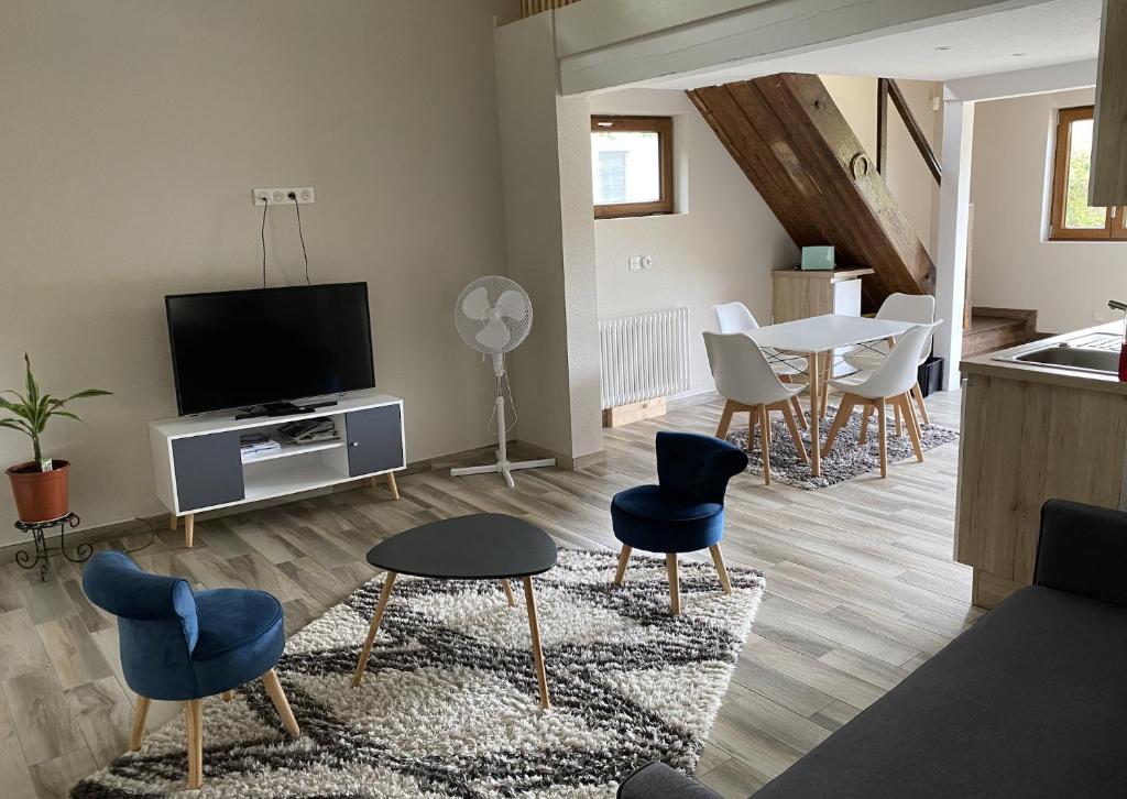 a living room with a tv and a table and chairs at l'ECURIE pour 6 personnes in Lebétain