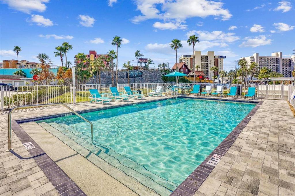 a large swimming pool with blue chairs and palm trees at Madeira Del Mar 205 in St. Pete Beach
