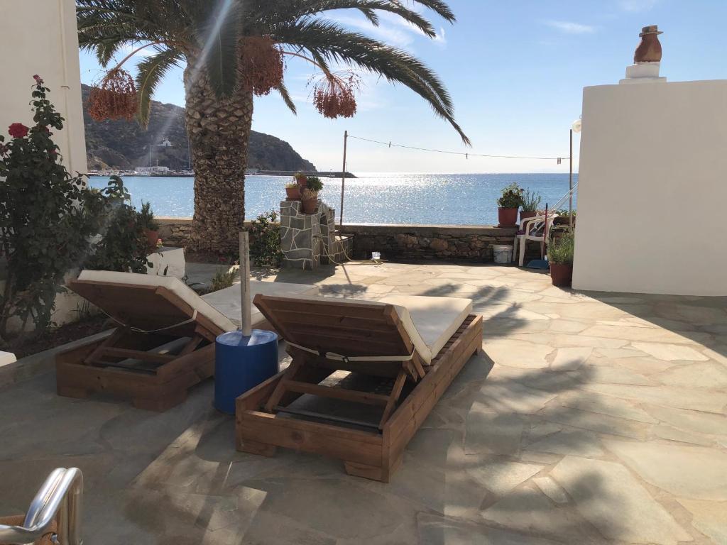 un patio con 2 sillas, una palmera y el océano en Petradi Sifnos, en Platis Yialos Sifnos