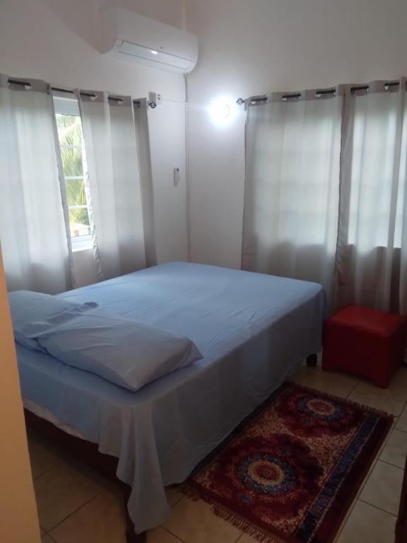 1 dormitorio con 1 cama con cortinas blancas y alfombra en A Piece of Paradise, en Santa Cruz