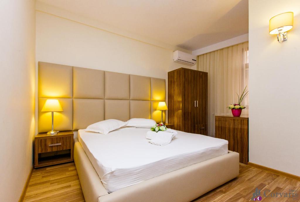 a bedroom with a large white bed and two lamps at Hotel Corvaris in Bucharest