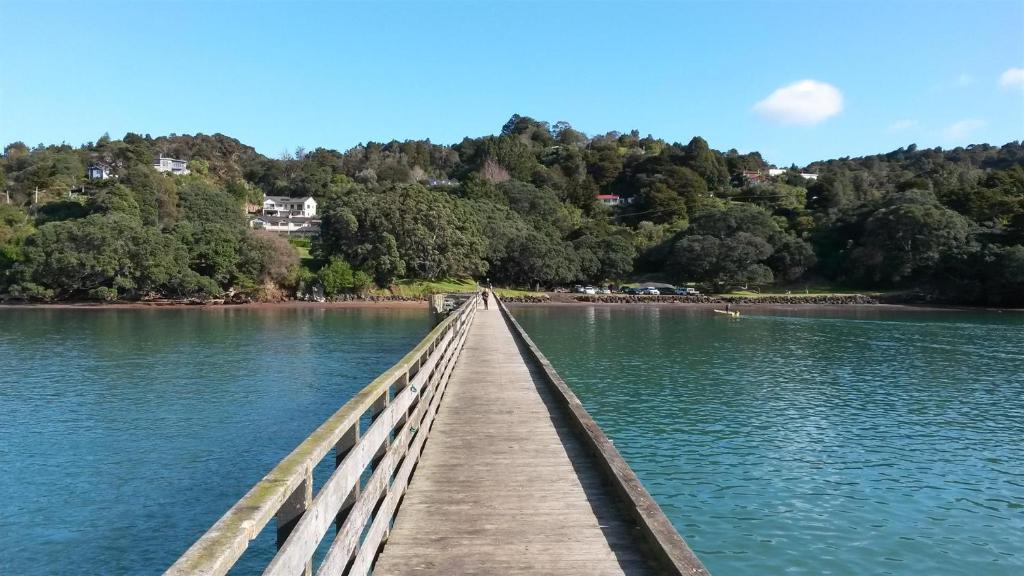 uma ponte de madeira sobre uma massa de água em Cornwallis Palms em Auckland