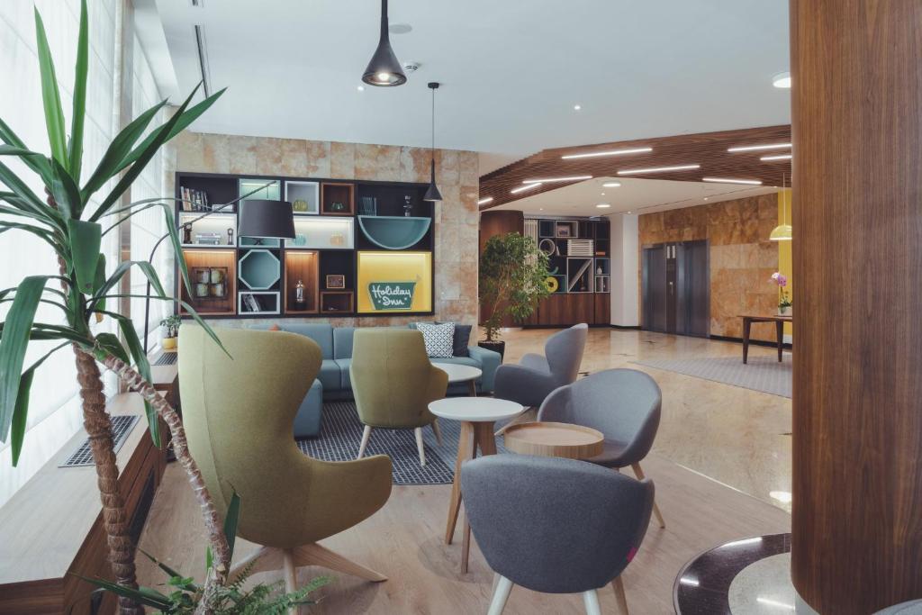 a lobby with chairs and tables in a building at Holiday Inn Skopje, an IHG Hotel in Skopje