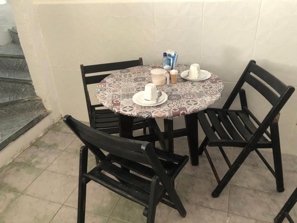 einen Tisch mit 2 Stühlen und einen Tisch mit Tassen und Untertassen in der Unterkunft Pousada Aconchego in Aracaju