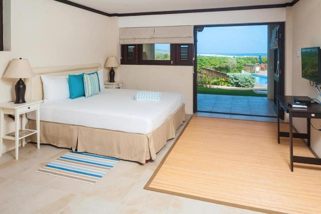 a bedroom with a bed and a sliding glass door at Santosha Barbados in Saint Andrew