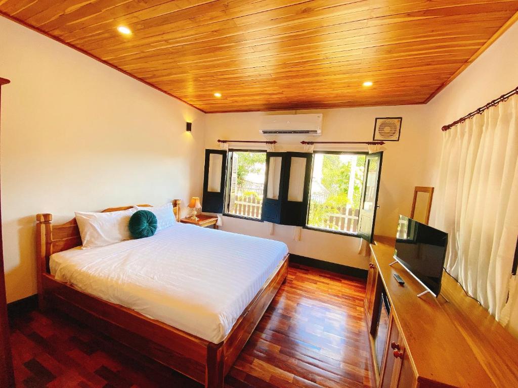 a bedroom with a bed with a wooden ceiling at Opera Premier Hotel in Luang Prabang