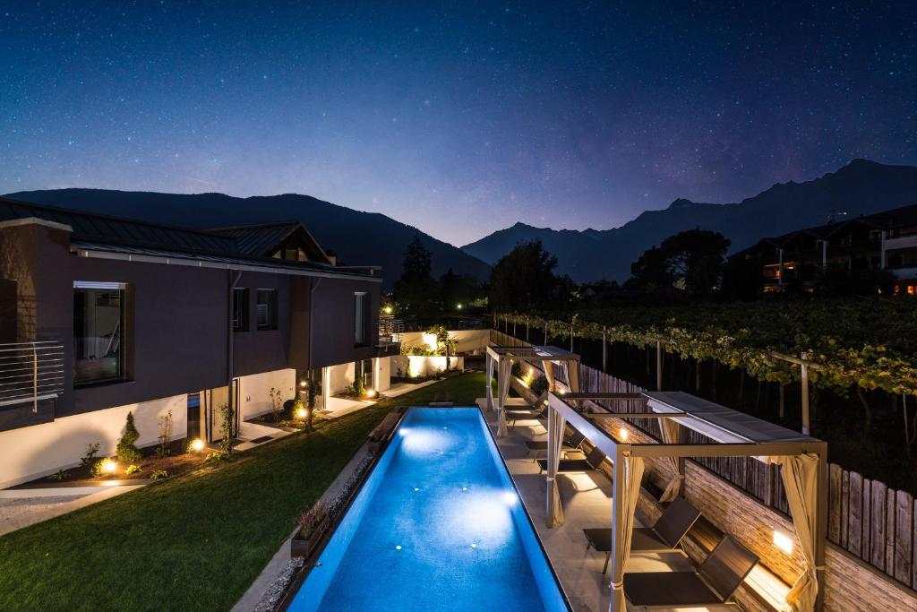 a backyard with a swimming pool at night at Merangardenvilla adults only in Merano
