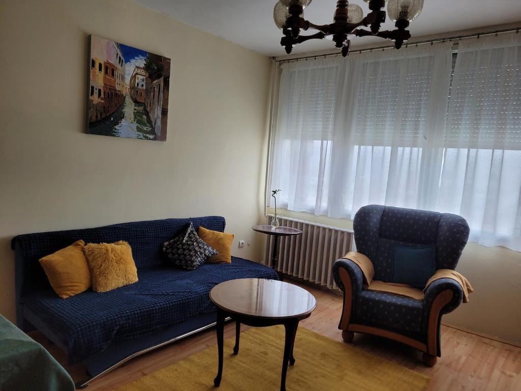 a living room with a blue couch and a chair at Sylvis Place in Gödöllő