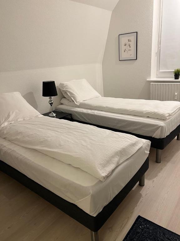 two twin beds in a room with a lamp at Lille Vedelsborg in Vejle