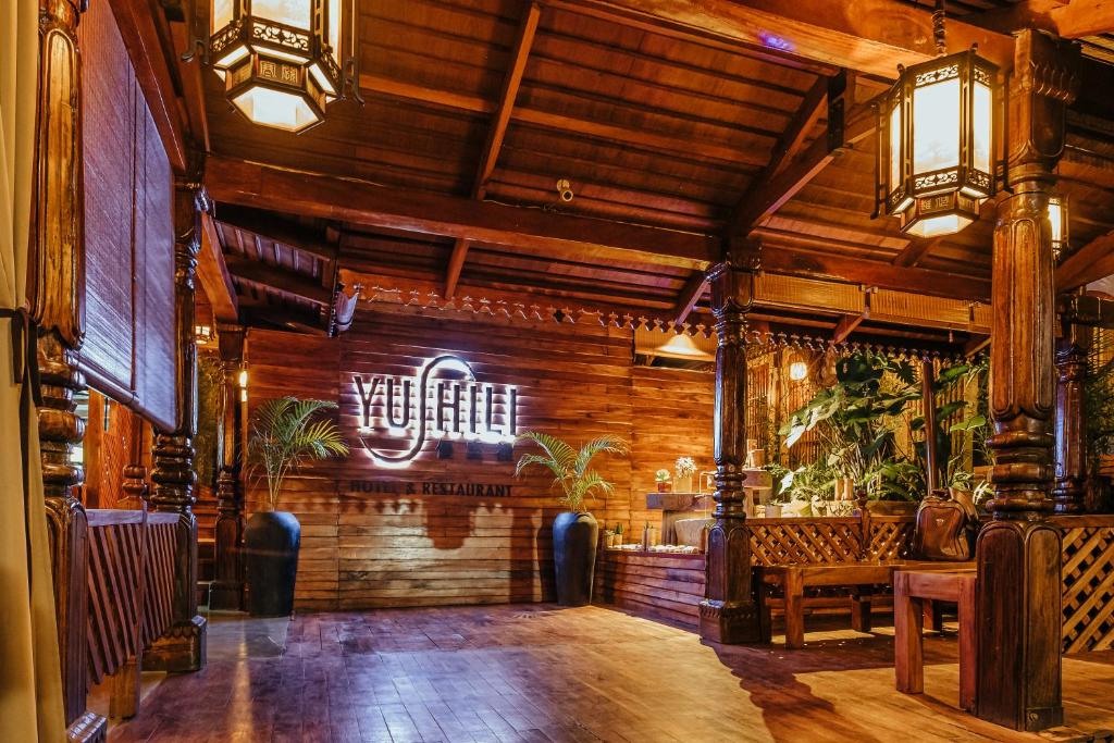 a restaurant with wooden walls and a bar with benches at Yushili Hotel Kampala in Kampala