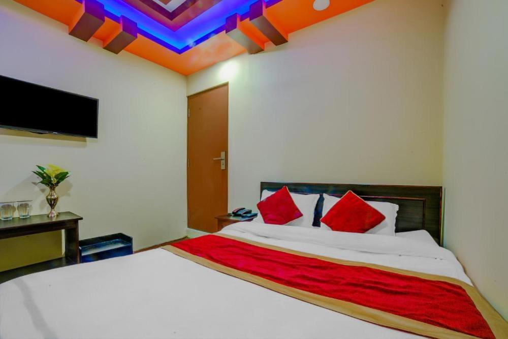 una camera da letto con un letto con cuscini rossi e una TV di Guru hotel and lodge a Itahari