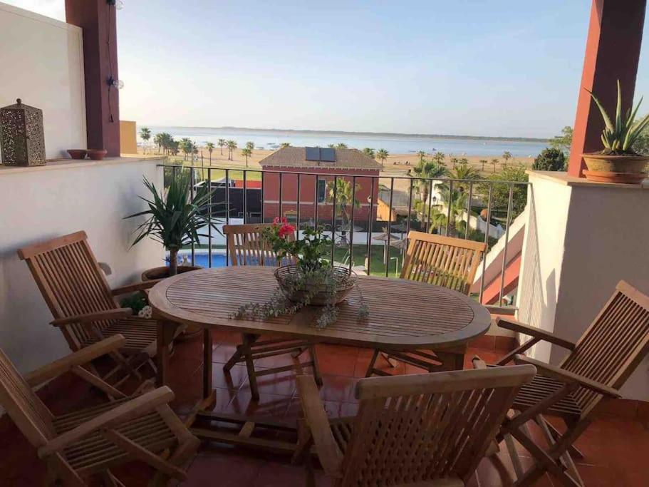 een tafel en stoelen op een balkon met uitzicht op de oceaan bij Sanlúcar Playa de las Piletas in Sanlúcar de Barrameda