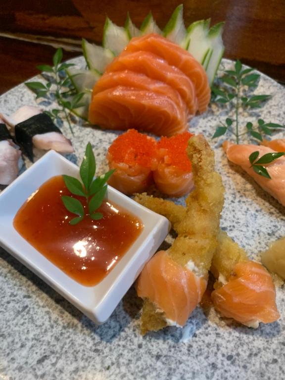 um prato de sushi com salmão e molho em Nômades Club House em Balneário Camboriú