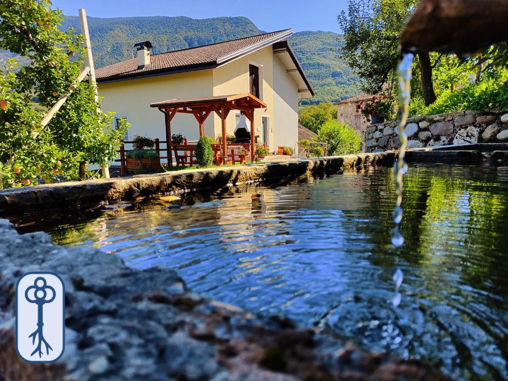 a house with a gazebo next to a body of water at Casa Vacanze Antico Eremo, tra natura e tradizione in Campodenno