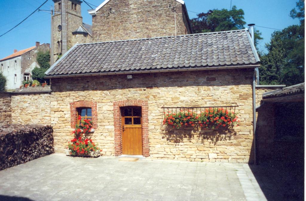 um edifício de tijolos com caixas de flores e uma porta em Gîte Le fournil em Modave