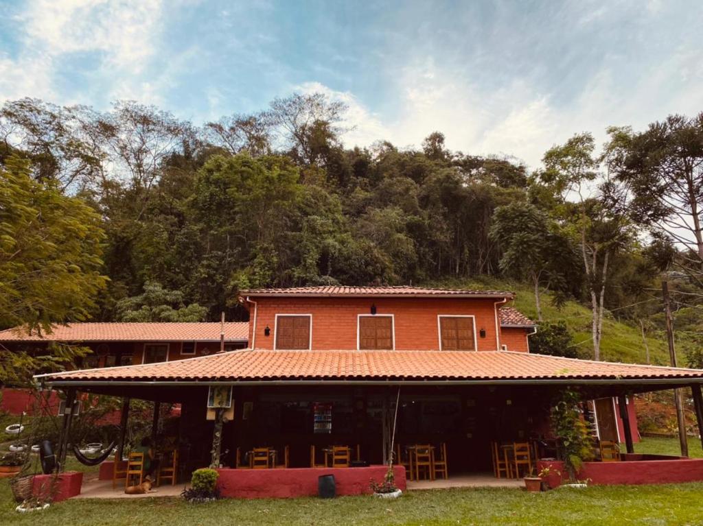 uma casa grande com cadeiras em frente em Pousada, Camping e Restaurante do Sô Ito em Santa Rita de Jacutinga