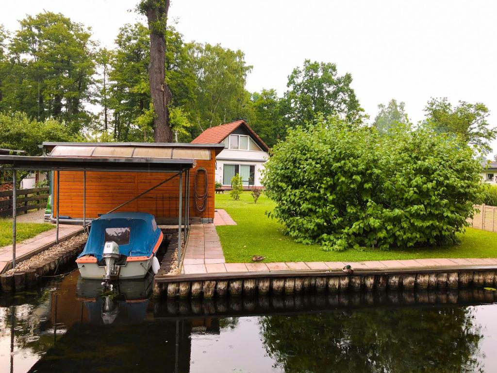 a small boat in the water next to a house at Ferienhaus direkt an der Spree mit Whirlpool und Sauna in Berlin