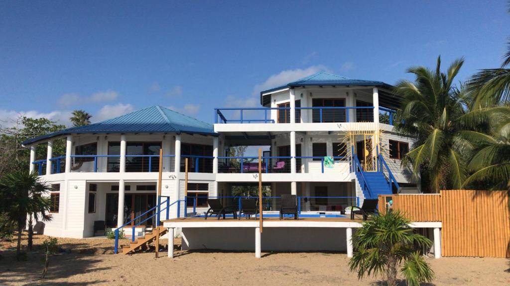 a large white house with a blue roof on the beach at Moonrise Beach in Placencia Village