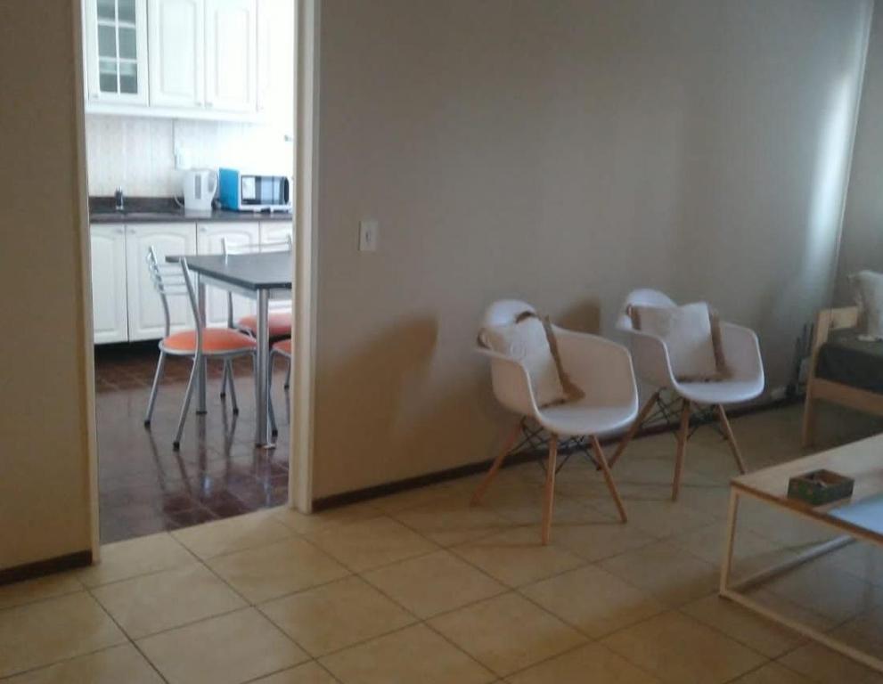 cocina con sillas blancas y mesa en una habitación en APART CIUDAD MENDOZA en Mendoza