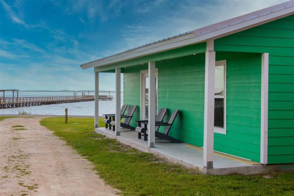 a green house on the beach with a pier in the background at Mallard in Rockport