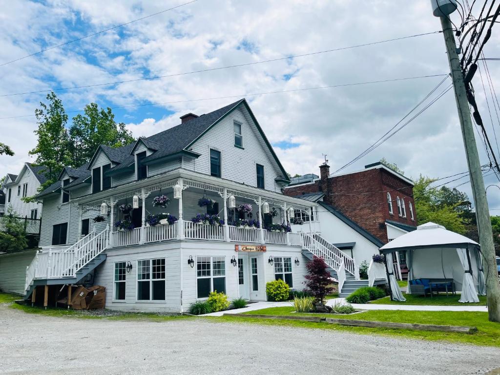 Casa blanca grande con balcón blanco en Sweet Home des Suites North Hatley, en North Hatley