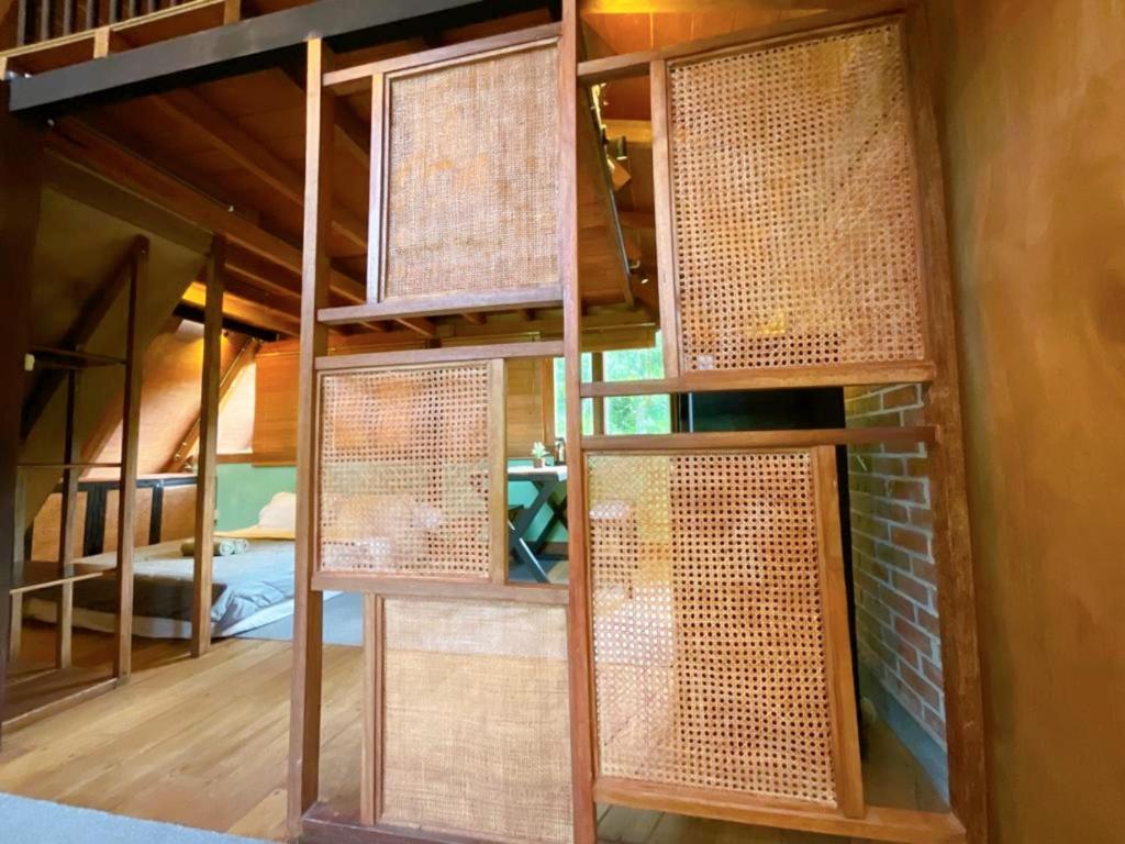 a room with a bunk bed with several windows at Comfortable Wood House second floor and attic in Kuta Lombok