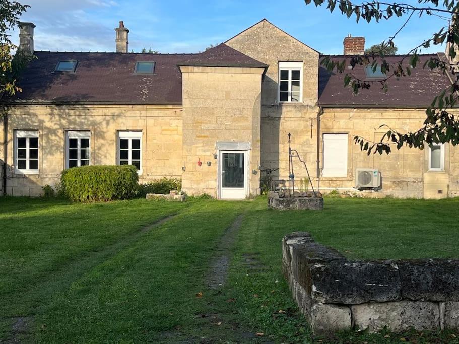 une grande maison en pierre avec une cour herbeuse dans l'établissement Gîte le Presbytère de Blérancourt, à Blérancourt