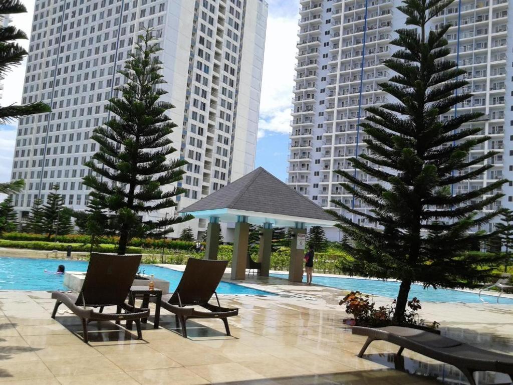 a pool with chairs and a gazebo and some buildings at Heaven Suites, Tagaytay Condominium, Wind Residences in Tagaytay