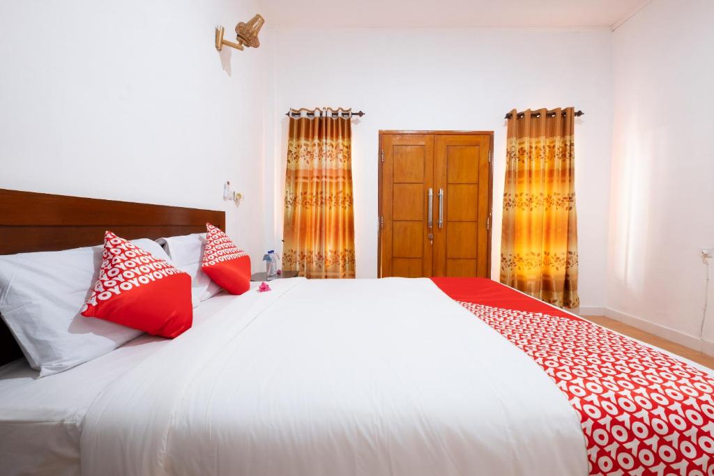 a bedroom with a bed with red and white pillows at Maringo cottage in Gili Trawangan