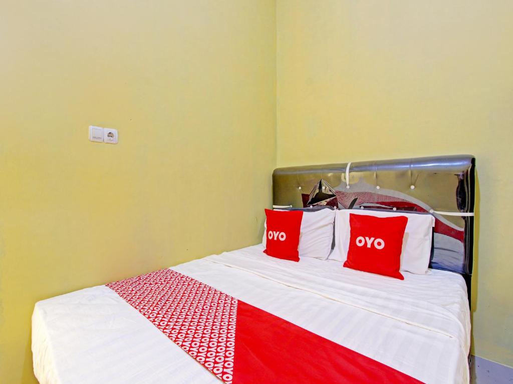 Una cama con dos almohadas rojas. en OYO 91818 Papaya Kos en Cilacap