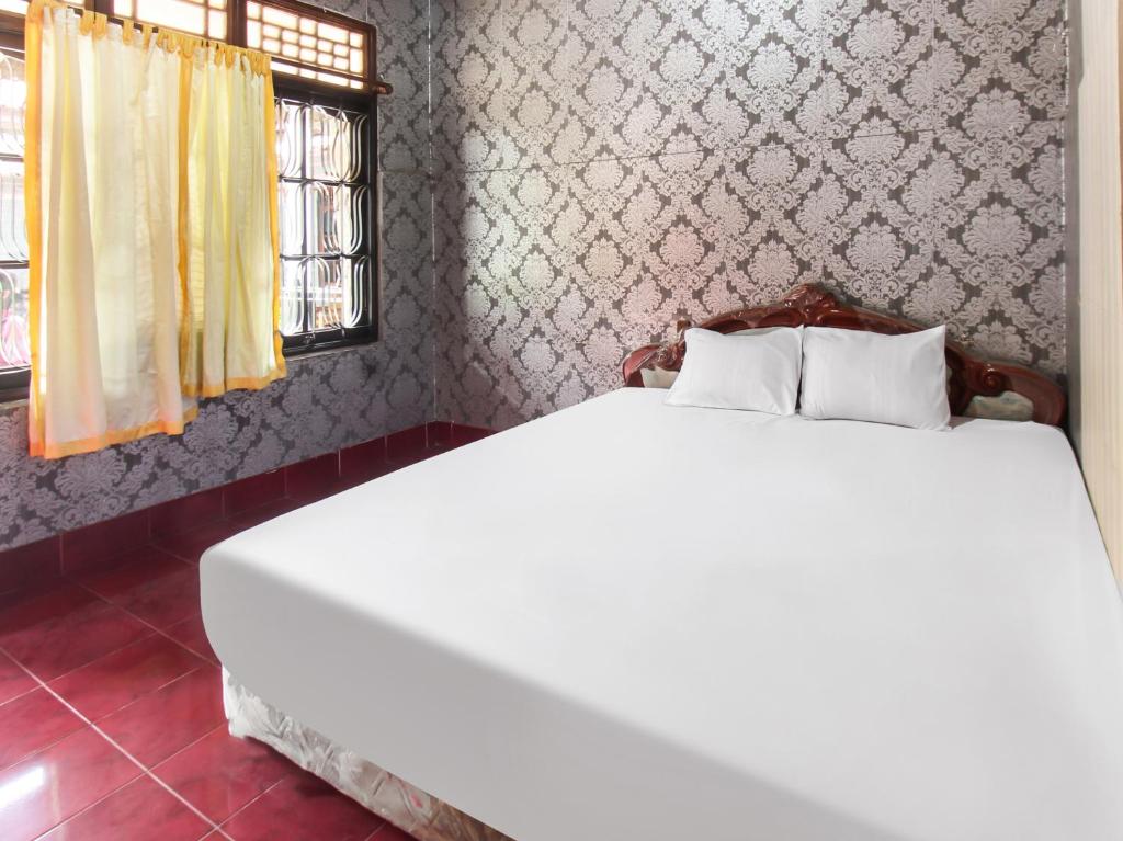 1 dormitorio con 1 cama blanca en una habitación en OYO 91829 Hotel Artha, en Tjakranegara
