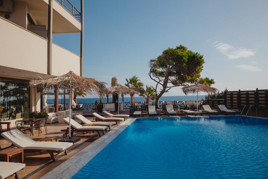 een zwembad met ligstoelen en de oceaan bij Mati Hotel in Mati