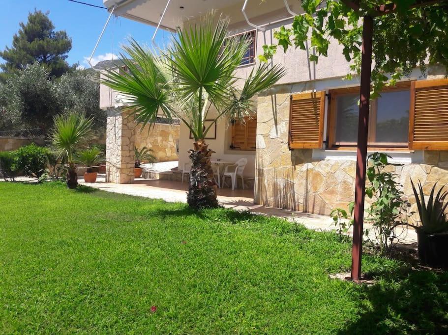 a house with a green yard with palm trees at Porto Vito in Aigosthena