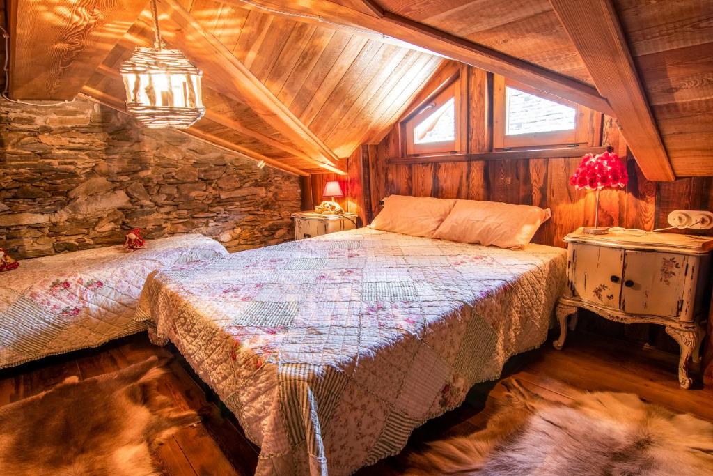 - une chambre avec un lit et un mur en pierre dans l'établissement Baita delle Bambole - 400 metri dal LAGO, à Isola