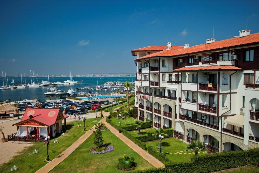 a large building next to a marina with boats at ARENA Apart Complex in Sveti Vlas
