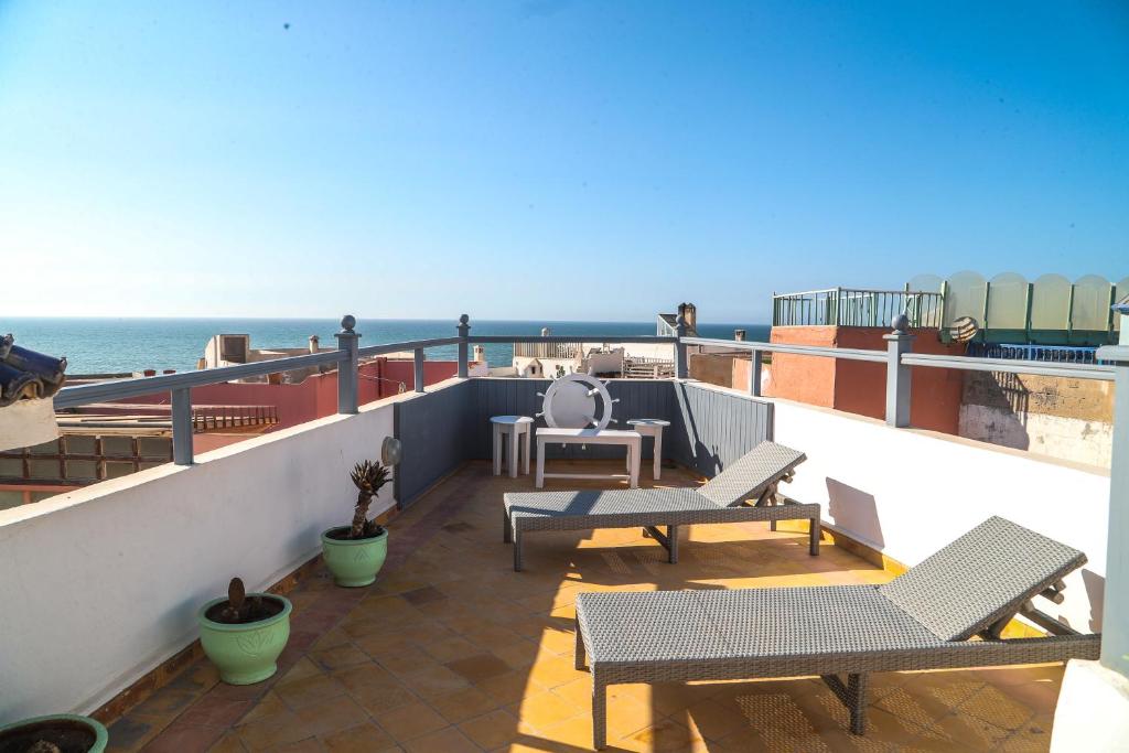 a balcony with tables and chairs and the ocean at Riad Dar Afram in Essaouira