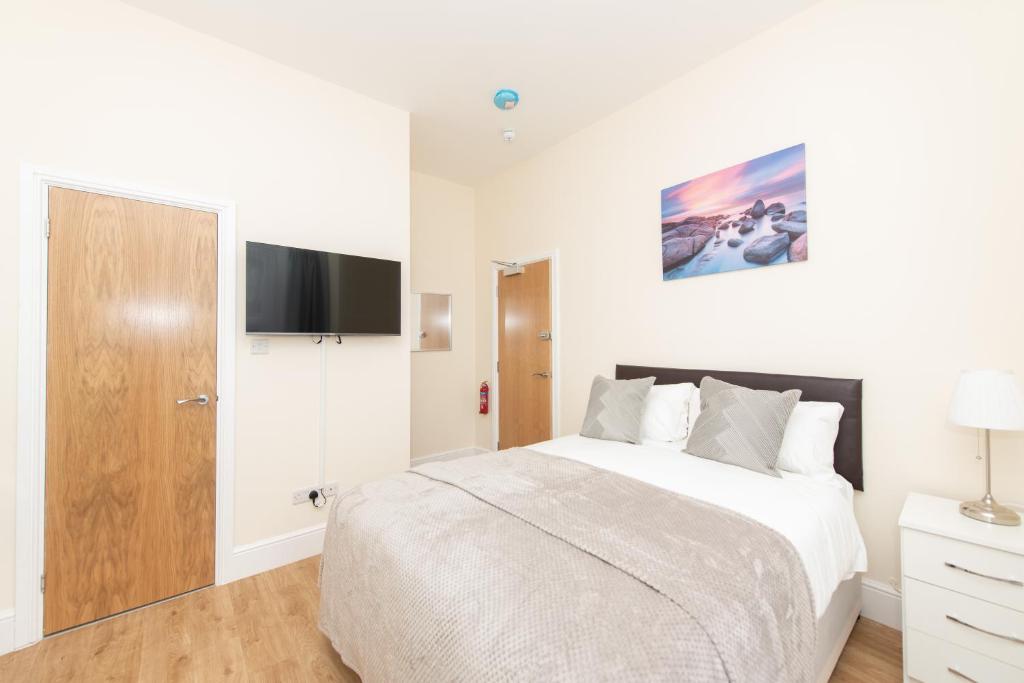 Un dormitorio blanco con una cama y un televisor de pantalla plana. en Luxury Shirley Apartments close to Solent Uni and Southampton Central Train Station, en Southampton