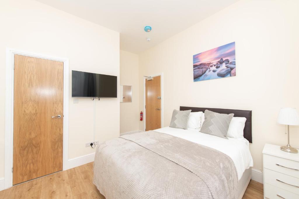 a white bedroom with a bed and a flat screen tv at Luxury Shirley Apartments close to Solent Uni and Southampton Central Train Station in Southampton