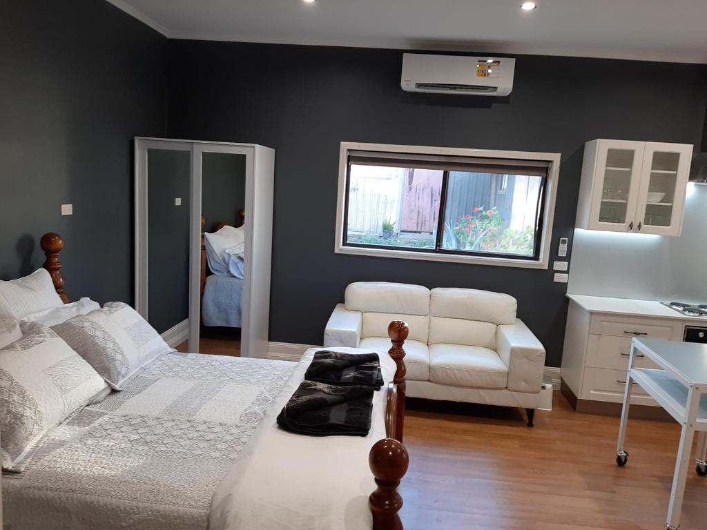 a bedroom with a bed and a couch and a chair at Maple Leaf Cottage in Dubbo