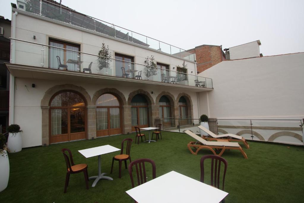 a patio with tables and chairs on a building at Hotel Cal Piteu in Guisona