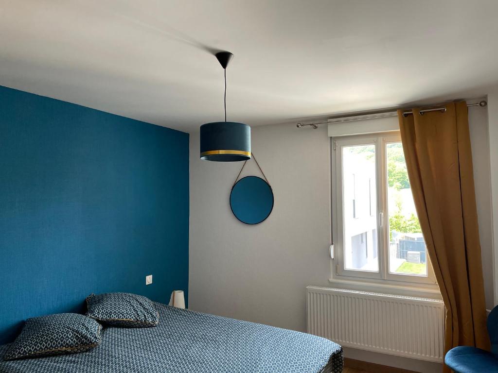 a blue bedroom with a bed and a window at Appartement Les Tilleuls &quot;3 étoiles&quot; in Niederbronn-les-Bains