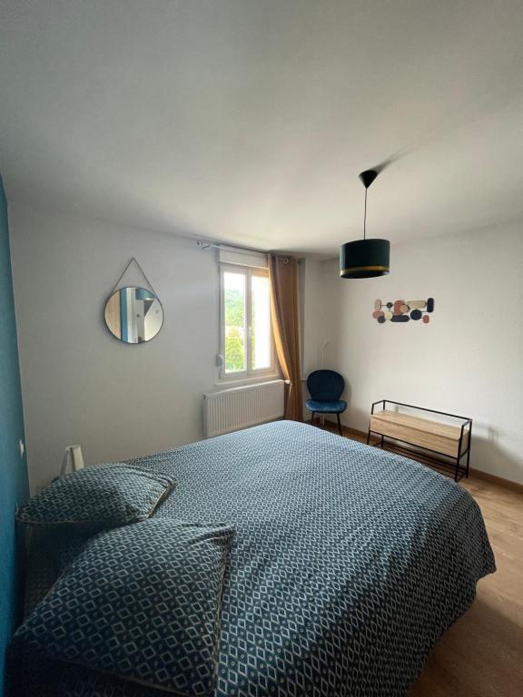 a bedroom with a bed with a blue comforter and a window at Appartement Les Tilleuls &quot;3 étoiles&quot; in Niederbronn-les-Bains