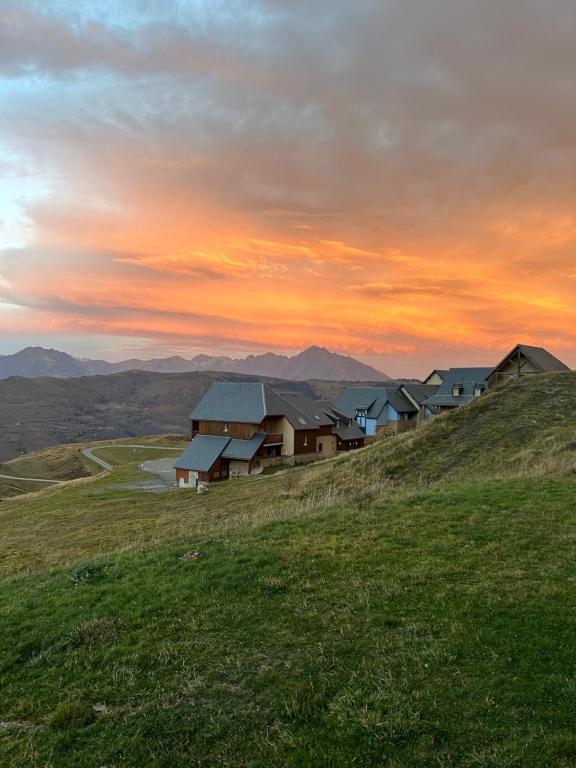 un grupo de casas en una colina al atardecer en Appartement 4 personnes - Hautes-Pyrénées- Village de Peyragudes Peyresourdes - Vue exceptionnelle sur la montagne en Germ