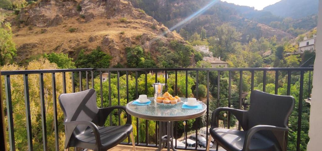 einen Tisch und Stühle auf einem Balkon mit Bergblick in der Unterkunft Alojamientos Puerta del Parque in Cazorla