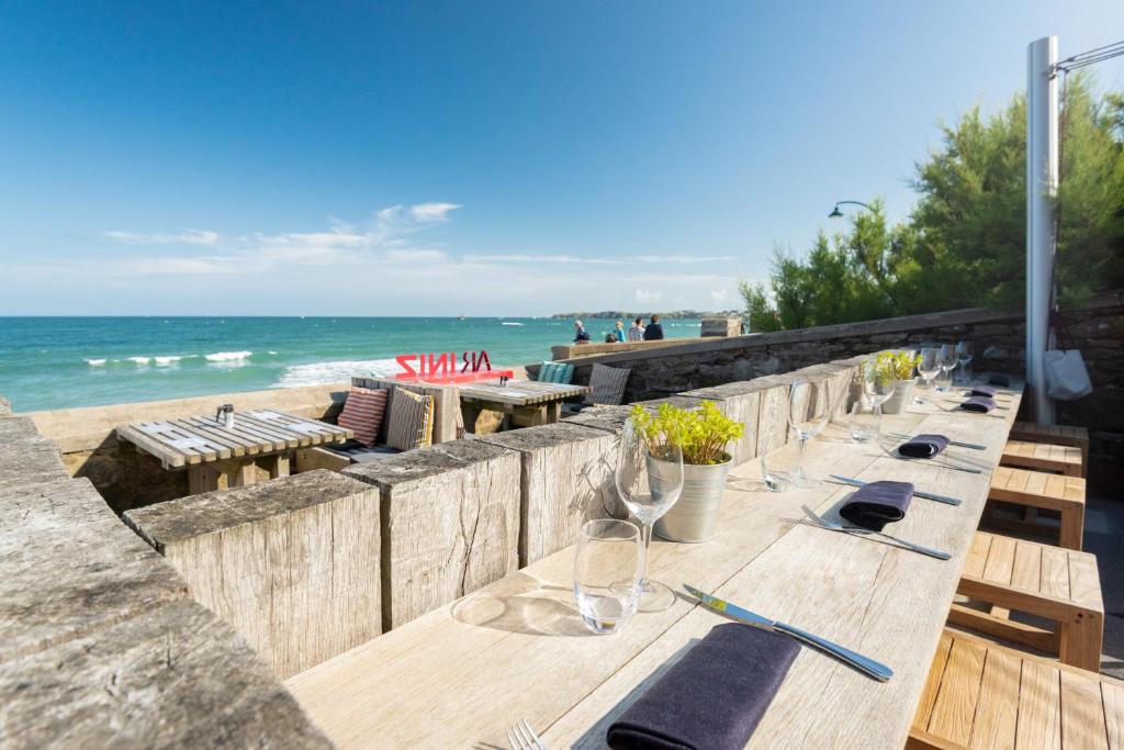 Hôtel Ar Iniz في سان مالو: طاولة خشبية طويلة مع كؤوس للنبيذ على الشاطئ