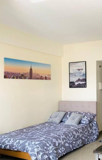 a bedroom with a bed with a picture on the wall at Mabolo Garden Flats 2306 in Cebu City